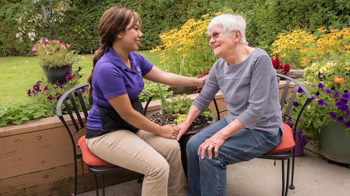 Caregiver speaking with resident in a garden area