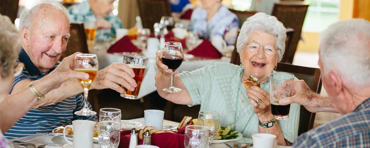 Older adults, laughing, eating food and cheersing