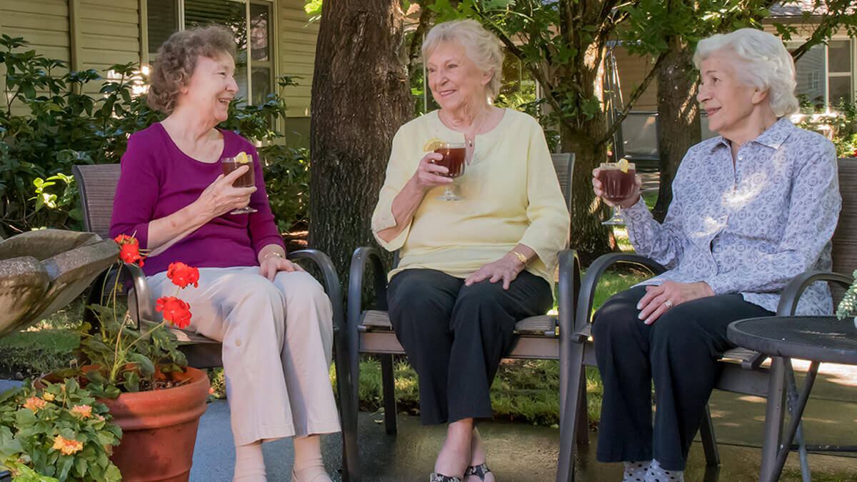 Three residents drinking tea on the terrace at the Wilsonville community
