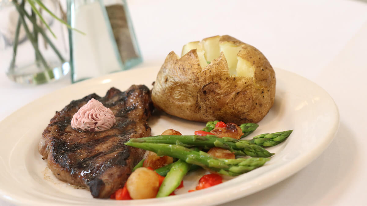 Gourmet meal with a grilled steak, baked potato and roasted vegetables at the Anna Maria community