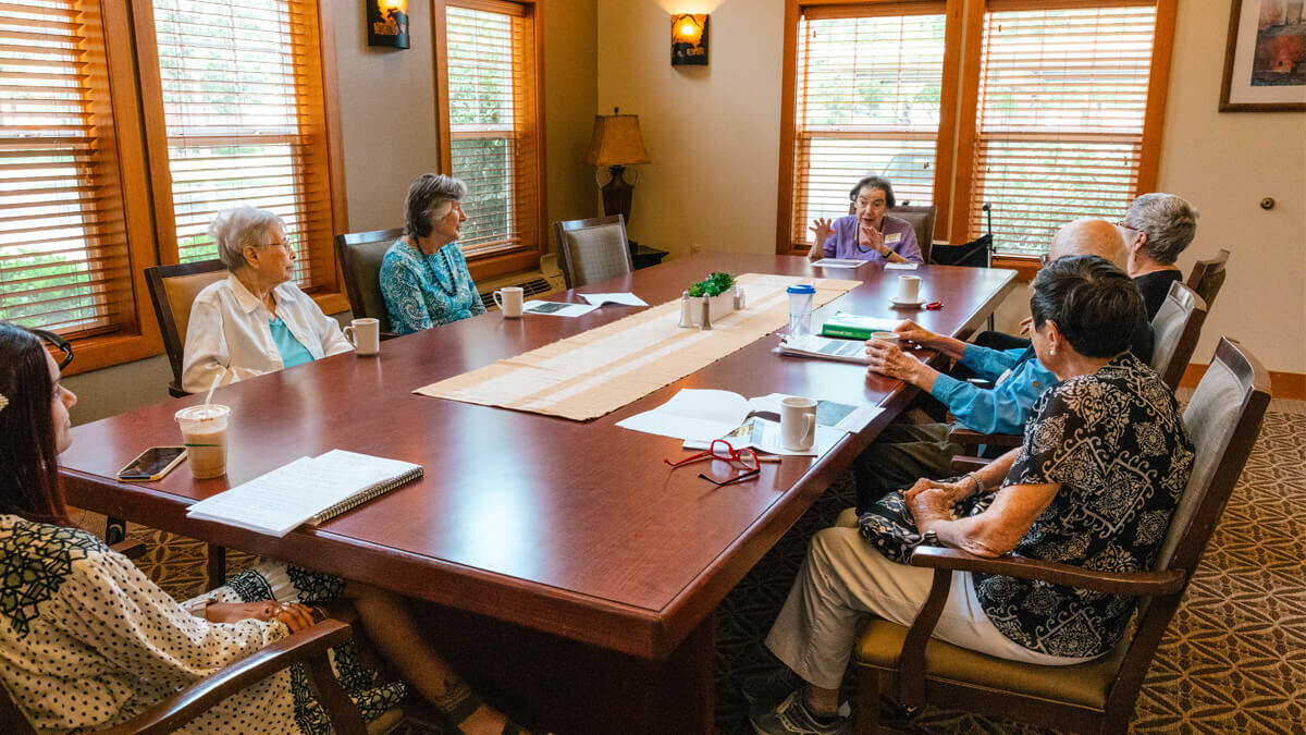 Group of residents enjoying a conversation around a large conference table at the Missoula community