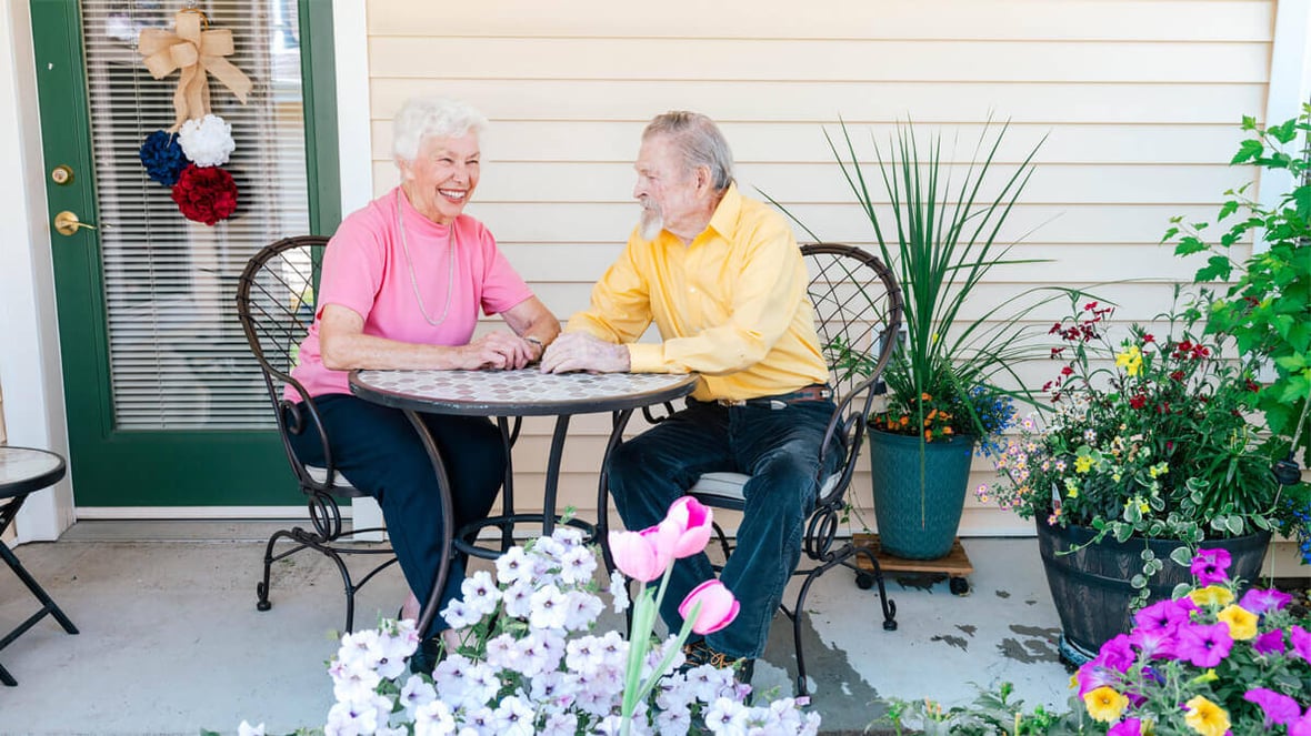 Two residents sitting on an outdoor patio at the Butte community