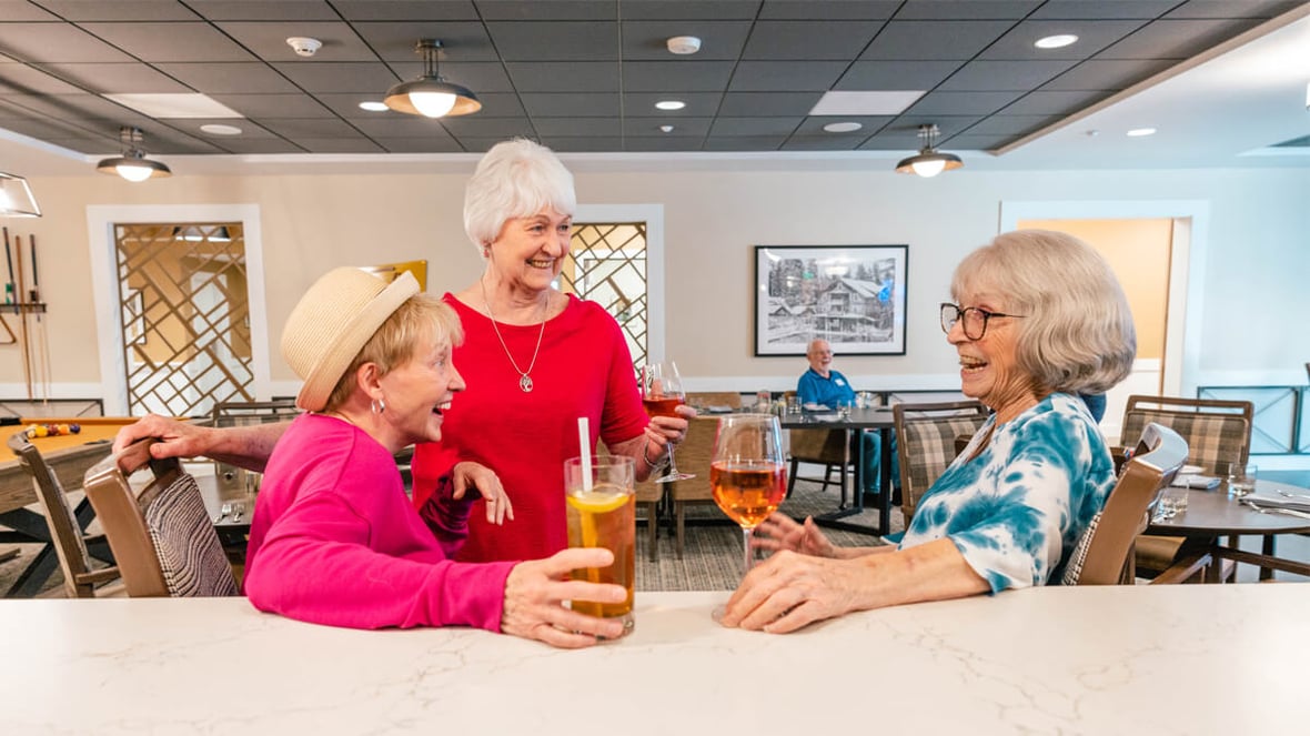 Three residents enjoying drinks at a bar at the Happy Valley community