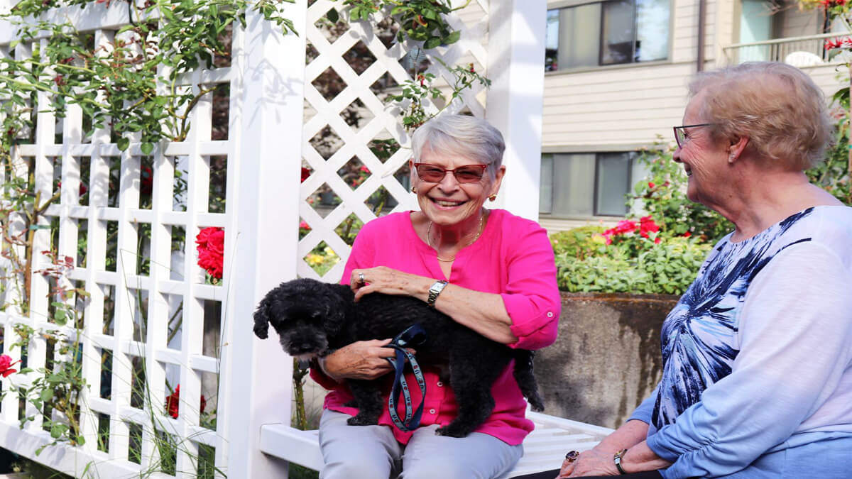 Two women sitting outside with a dog