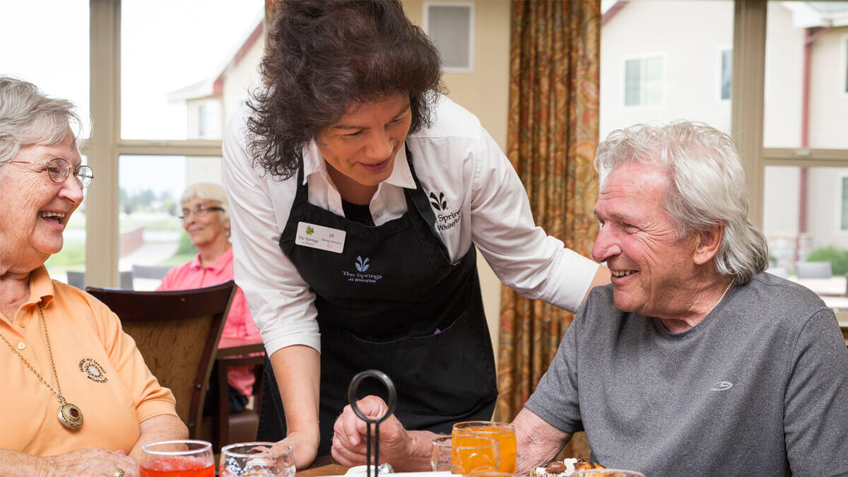 Residents being served in the dining room at the Whitefish community