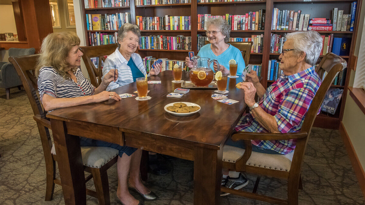 Group of women playing cards in the library area at the Sherwood community